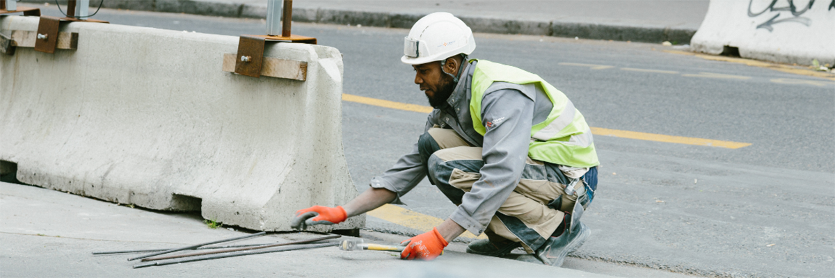 Road construction worker in a hard hat, placing concrete barriers