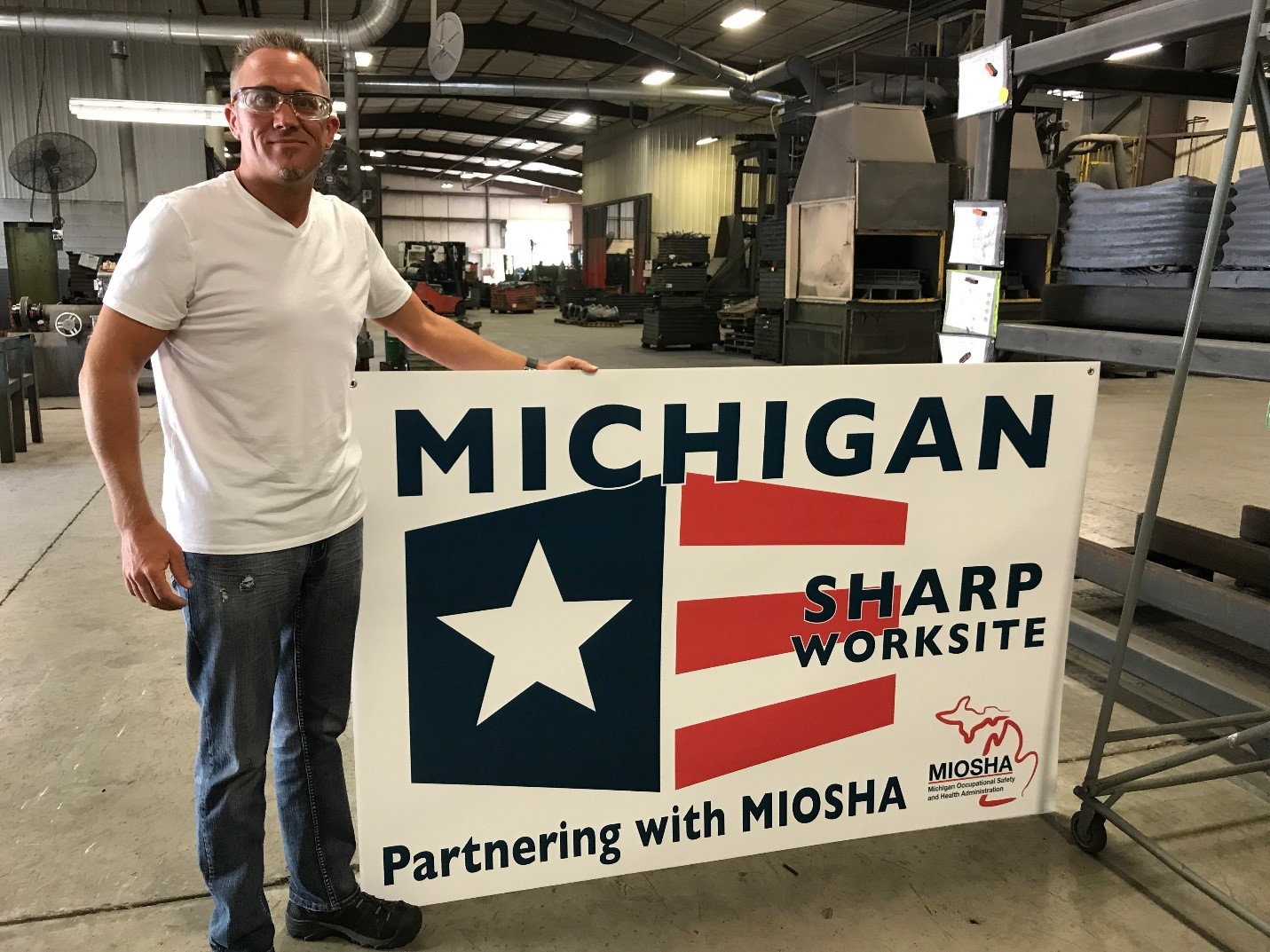 Mark Swanson, Quality/Safety Manager, with SHARP Banner