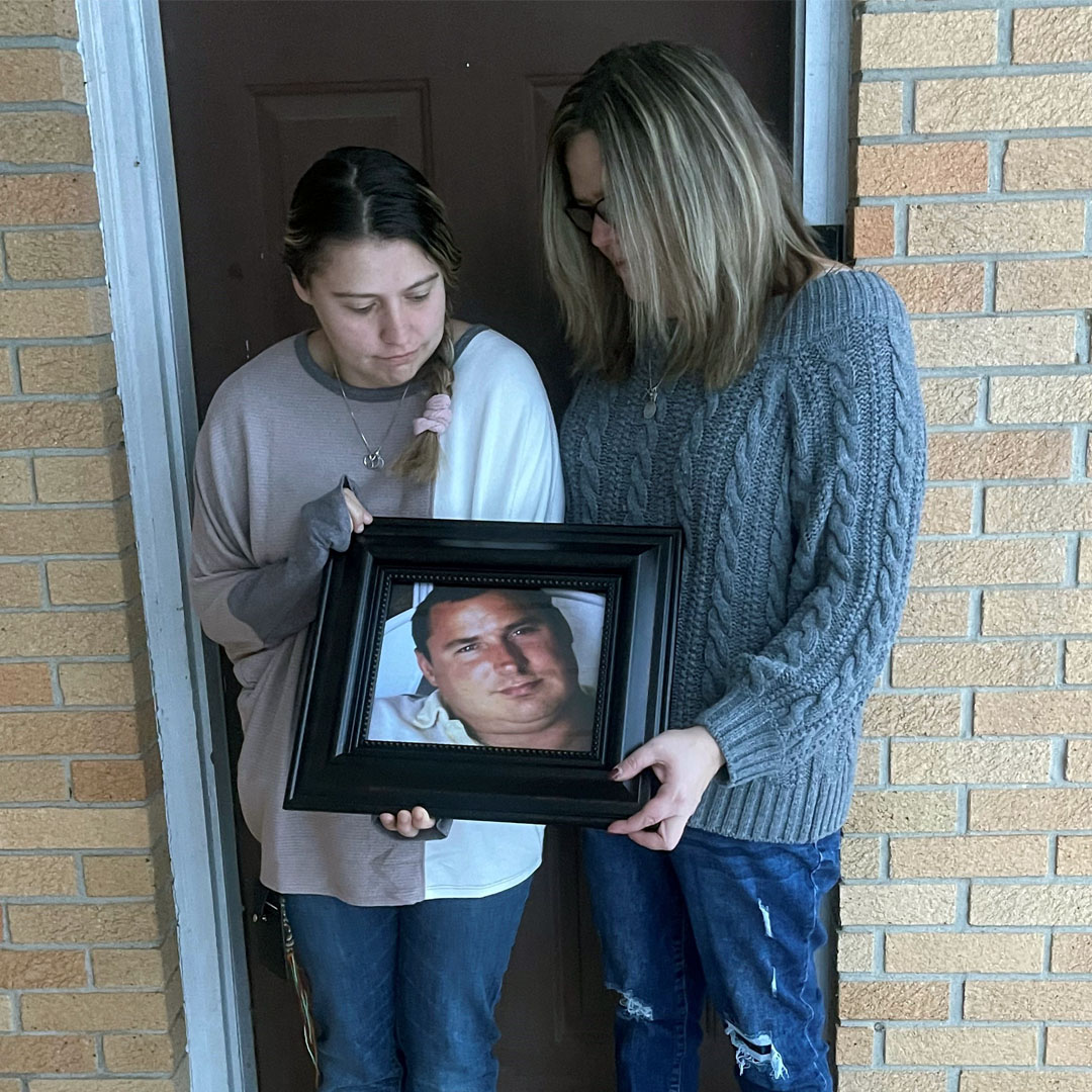 Individual holding up photo of a fallen worker