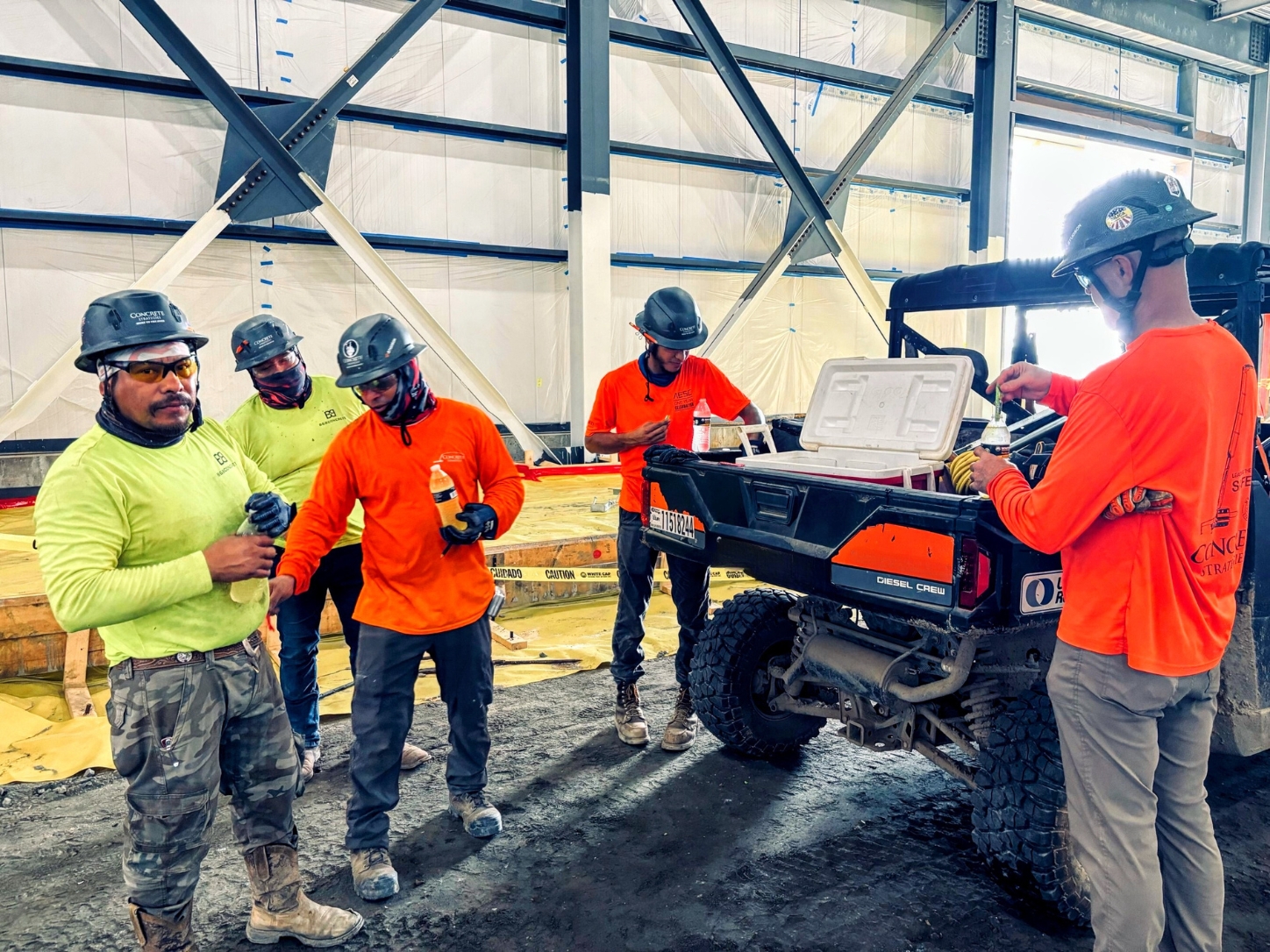 Concrete Strategies : safety specialist is driving a jobsite utility vehicle with a cooler of cold water to hand out to workers