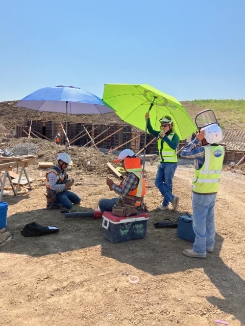 HEI Civil : workers are using two umbrellas to maximize shade coverage