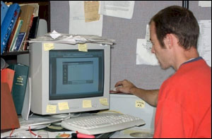 Figure 1. Poor workstation setup. This person must reach up and away from his desk to operate the mouse.