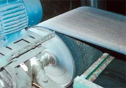 Unguarded nip point between belt and pulley on belt conveyor.