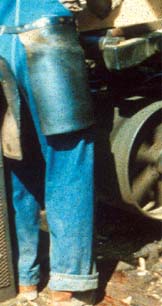 Worker next to unguarded spoked pulley on belt conveyor.