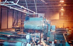 Workers standing inside edger changing saw blades: saw must be locked out at main disconnect.