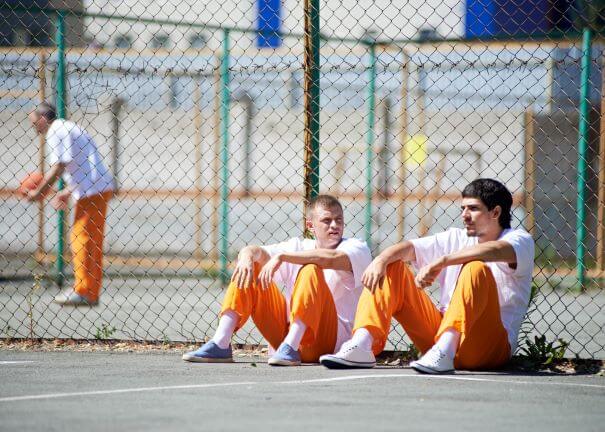 three men in orange jumpsuits