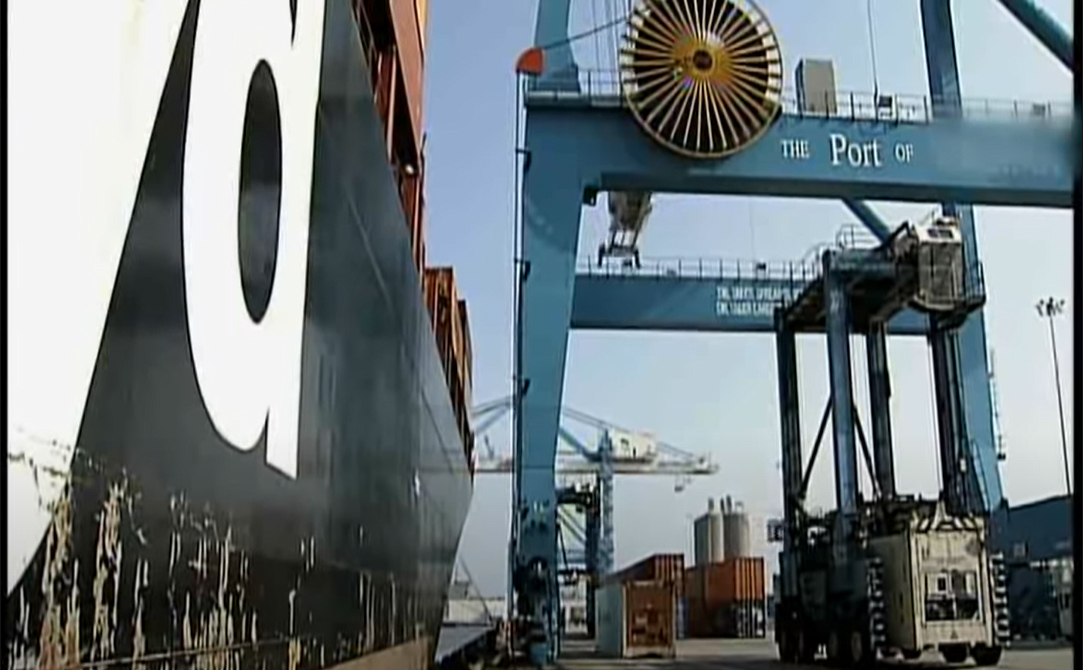 Container ship docked next to a top loader