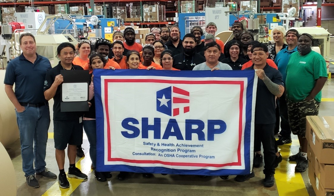 Members of management and the production team pose with their latest SHARP flag.