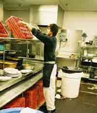 worker handling an elevated dish rack.