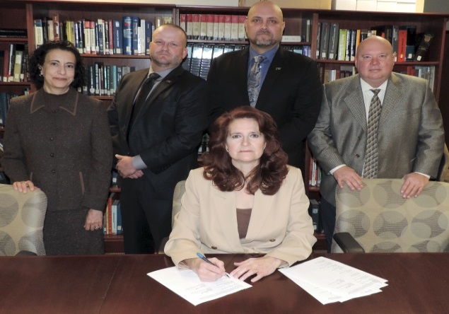 OSHA Regional Administrator Kimberly Stille (seated) joins (from left) OSHA Acting Deputy Regional Administrator Dee Cantu, Business Manager for Local Union No. 10 Dave Coleman, President and Director of Training for the MO-KAN Ironworkers Apprenticeship Training Fund Brian Garrett, and Executive Director of Safety and Health for the Ironworkers International Steve Rank, for the signing of the partnership agreement.