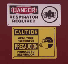 Danger sign regarding a respirator being required and a Caution sign in English/Spanish noting wear your respirator