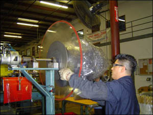 Figure 26. Employee with appropriate PPE (gloves, sleeves) removing full web roll.