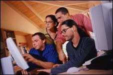 Group of people surrounding computer screen; The internet may be a valuable source of information during an emergency.