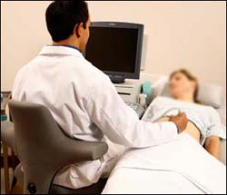 The patient is close to the sonographer, minimizing reach. The chair is higher and the sonographer's eyes are level with the top of the monitor.