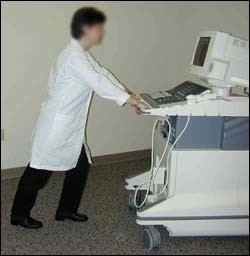 Figure 6. Sonographer using proper body mechanics to move ultrasound equipment.