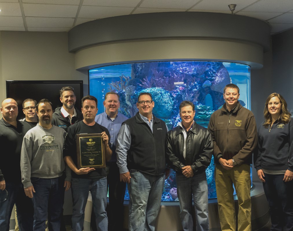 Reynolds Polymer Team with SHARP Plaque.  Left to right: Will Simpson- Plant Manager, Mark Johnson- Vice President of Sales, Bill Raimer- Chief Financial Officer, Paul Gardner- Vice President of Engineering, Matt Johnson- Safety Manager, Bryan Barboe- Director of Operations, Bart Baker- Vice President of Global Operations, Scott Sullivan- President, Casey Barnes M.S., CSP – Colorado State University On-Site Consultation Program Safety Consultant, and Layne Sargent M.S., CIH, CSP – Colorado State University On-Site Consultation Program Health Consultant