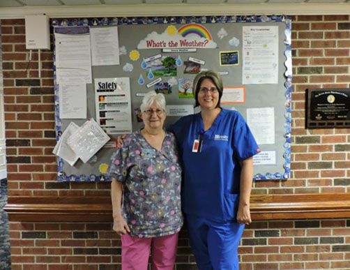 Safety committee members in front of the safety bulletin board (Nora Penn and Jennifer Wilson, pictured).