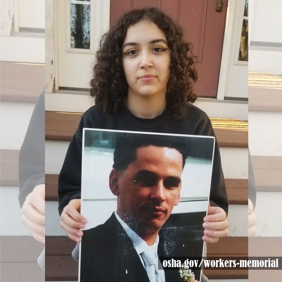 Individual holding up photo of a fallen worker