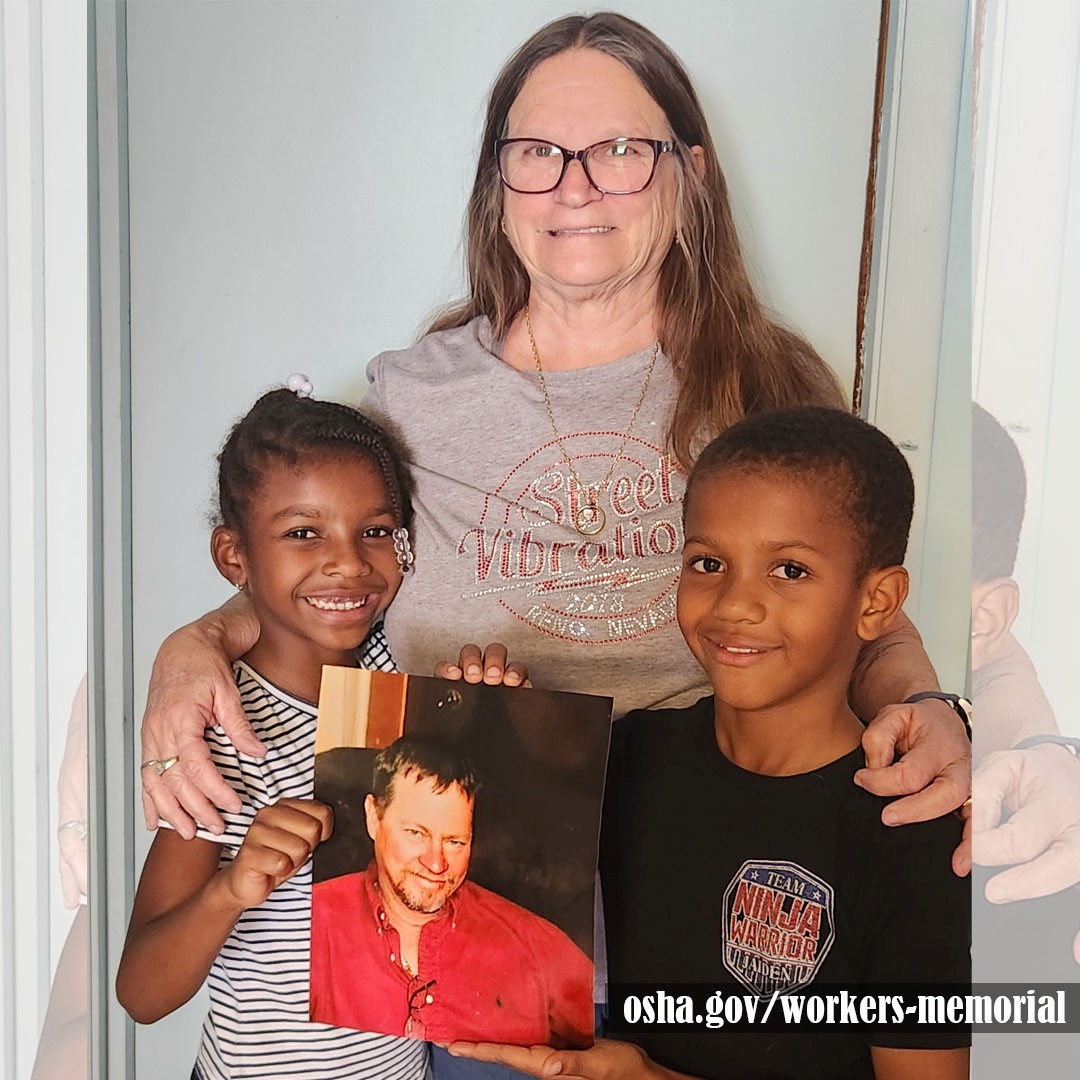 Individuals holding up photo of a fallen worker