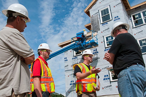 Photo by Karen Bachelder  Matt Hardy (center) chats with Gus Gustafson, construction manager/site supervisor at A.W. Rose Construction (right), as intern Brady Keene looks on. Gustafson has utilized the free on-site consultation service since getting fined by OSHA for improper window protection.