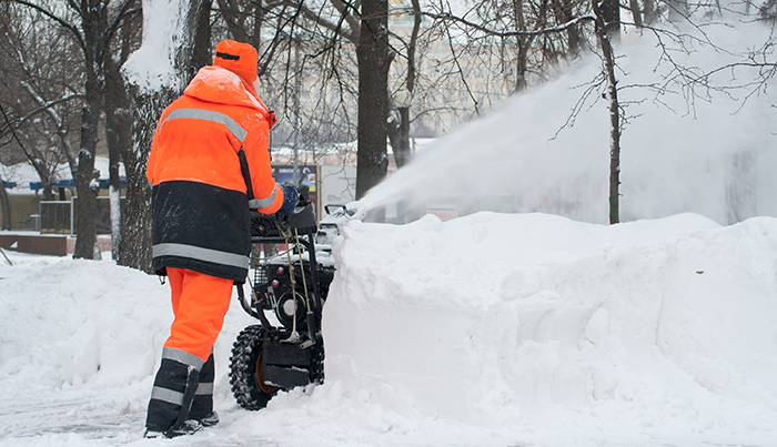 Worker using snow blower