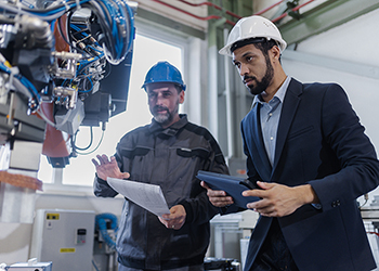 OSHA safety consultant and mechanic worker doing on-site consultation in industrial factory